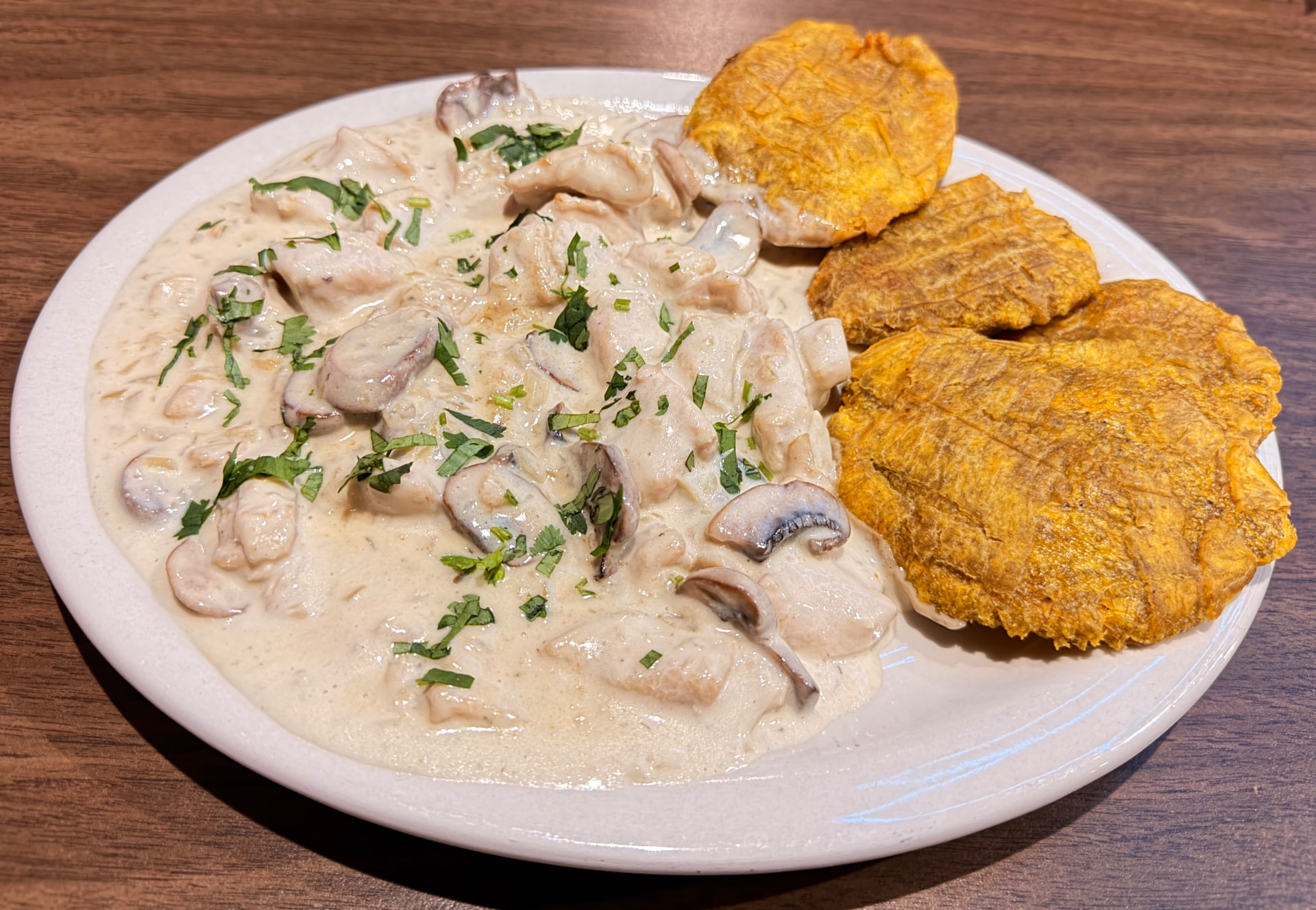 Pollo en salsa de champiñones cremosa con cilantro y tostones